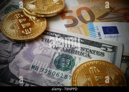 Bitcoins, an virtual currency in physical form, displayed on US-Dollar and Euro banknotes Stock Photo