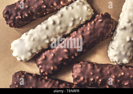 Dark and white chocolate bars with nuts on wrapping paper, top view Stock Photo
