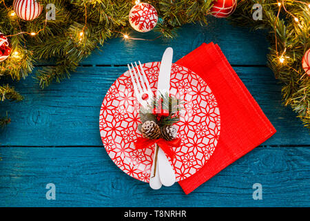 Photo of pine branches, plates with red pattern, fork, knife, Christmas decoration, napkin Stock Photo