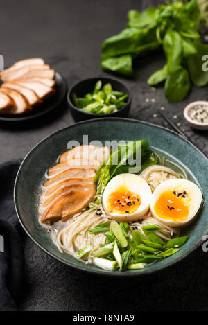 Japanese Ramen noodle soup with chicken on black background. Vertical orientation Stock Photo