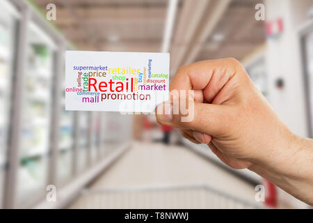 Hypermarket or supermarket employee man presenting white card with colourful words and big retail text closeup Stock Photo