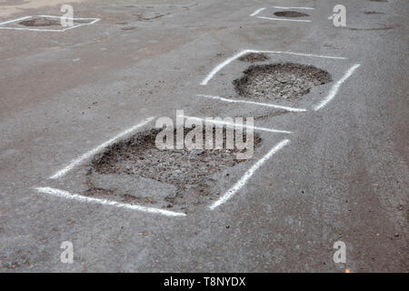 Potholes in a road marked for repair with paint Stock Photo