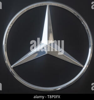Braunschweig, Germany, April 7., 2019: Logo of the Mercedes Daimler Benz brand from a chrome star with three teeth against a dark background. Stock Photo