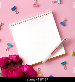 Flat lay picture with blank open notepad and different accessories on colored surface. Feminine workspace with  flowers Stock Photo