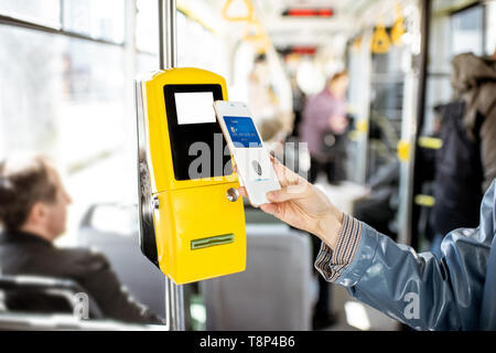 Paying conctactless with smartphone for the public transport in the tram, close-up view Stock Photo