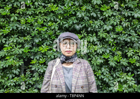 Fashionable Taiwanese woman of Chinese ethnicity against backgorund greenery Stock Photo