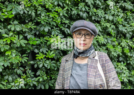 Fashionable Taiwanese woman of Chinese ethnicity against backgorund greenery Stock Photo