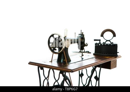 Antique sewing manual machine and old coal iron - vintage tailors tools - concept on white background Stock Photo