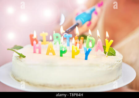 Woman lightning candles on birthday cake Stock Photo