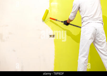 Painter use paint roller on new restored wall. Painter painting house interior Stock Photo