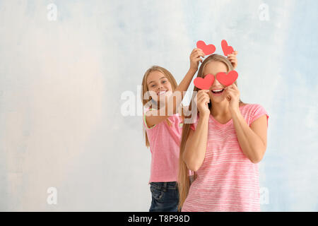 Cute little girl and her mother with red hearts on light background Stock Photo