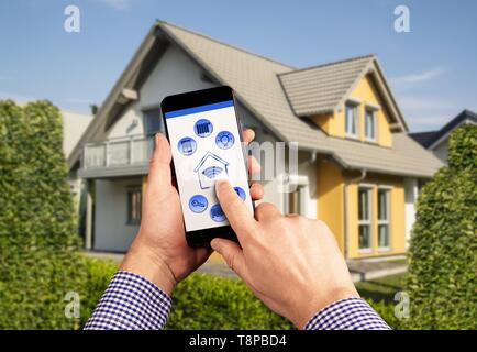 A remote control with icons for operating a smart home with house in the background | usage worldwide