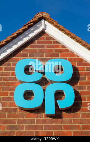 A brightly coloured Co-op sign against a blue sky on the gable end of one of their shops Stock Photo