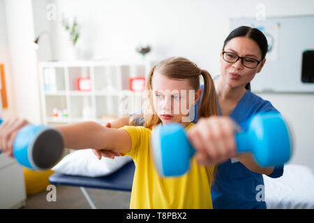 Pleasant good-looking medical worker in clear glasses correcting posture Stock Photo