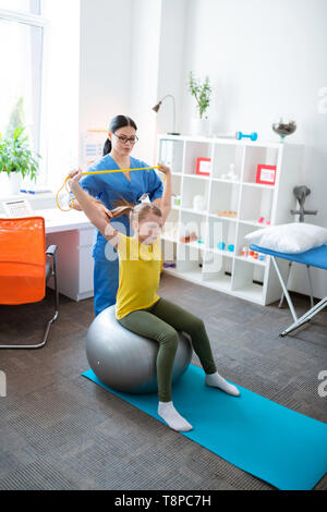 Experienced Asian physical therapist using different tools and equipment Stock Photo
