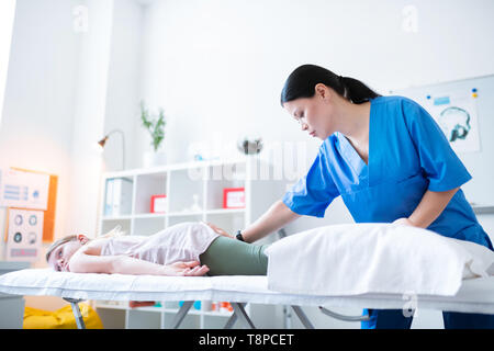 Experienced Asian therapist rubbing lying girl while staying in cabinet Stock Photo