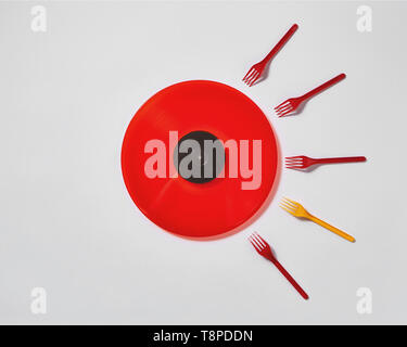 Red vinyl record with plastic colorfut forks on a gray background. Stock Photo