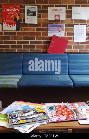 An empty waiting room & advice posters on the wall seen in an NHS local doctors surgery waiting room in Warwickshire, UK, On May 14, 2019. Stock Photo