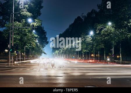 Motorcycles waiting on crossroad. Light trails of traffic in city. Hanoi at night, Vietnam. Stock Photo