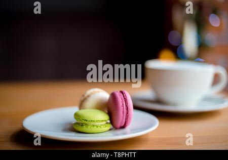 French macaroons on wooden table . Three merengue pastry in cafe for dessert. Stock Photo
