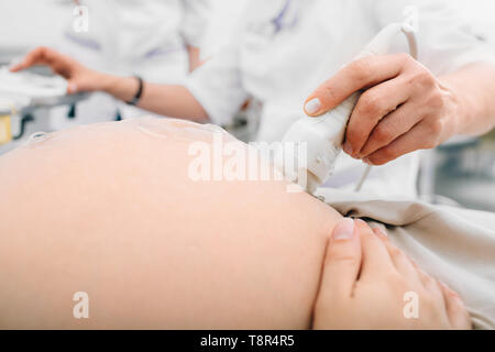 Pregnant woman having sonogram at clinic. Pregnancy ultrasound scan, stomach close-up Stock Photo