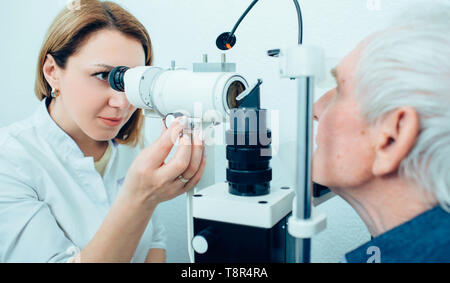 Senior man visiting optician, eye exam at clinic Stock Photo