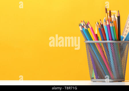 A set of stationery on the table. Pencils, brushes, paints on the background of the yellow wall. The concept of education, study. Copy space. Stock Photo