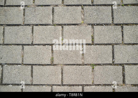 Texture of Concrete Paving Detail with Grass Growing from Cracks Stock Photo