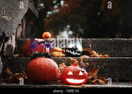 Halloween pumpkins with creative decorations on stairs outdoors Stock Photo
