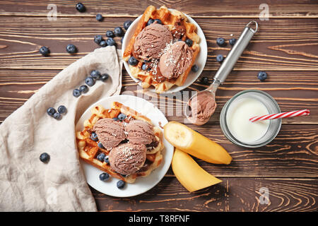 Delicious waffles with blueberries, ice cream and glass of milk on wooden table Stock Photo