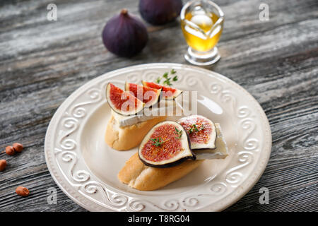 Tasty sandwiches with ripe fig and brie cheese on plate Stock Photo