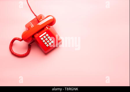 Top view of red telephone on pink desk or background, waiting phone call, phone ringing, vintage, classic red telephone. Stock Photo