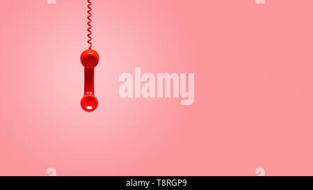 Red old telephone receiver hanging on pink background with texting space, waiting for phone call, vintage telephone. Stock Photo