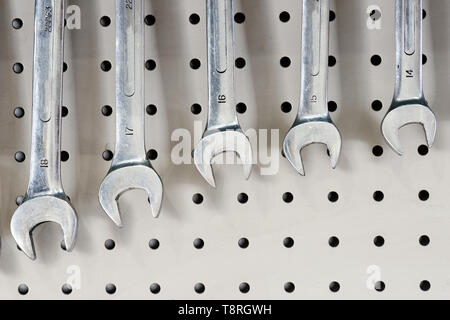 A set of chrome metal spanners hanging on a a board in a mechanics workshop. Stock Photo