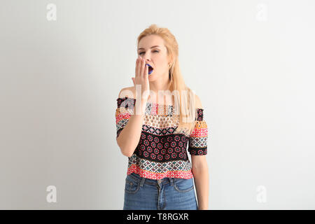 Portrait of beautiful yawning woman with unusual lipstick on white background Stock Photo