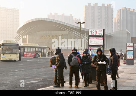 Passengers wait in queue line for public bus in parking area of Harbin West Railway Station Stock Photo