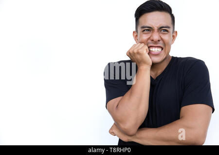 Frustrated young man holding hand on his cheek while standing on white background. Medical concept. Stock Photo