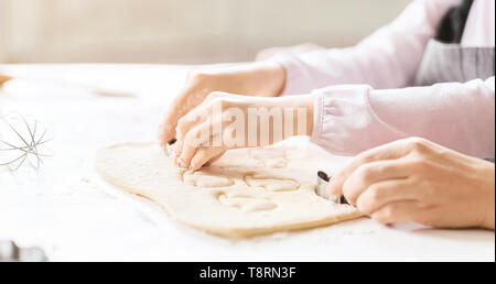 Mother And Daughter Cutting Dough With Different Cookie Shapes