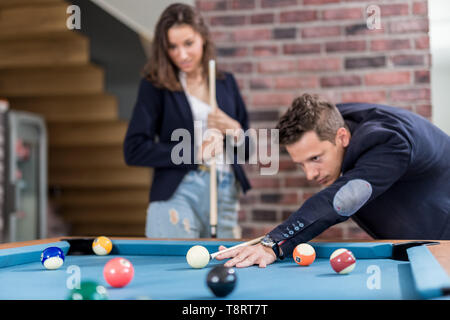 Young modern couple playing pool table billiard game. Stock Photo
