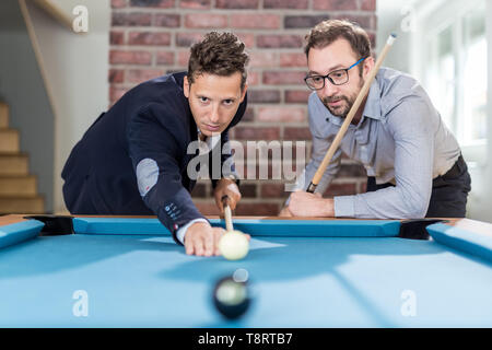 Two fashionable men friends playing billiard game. Stock Photo