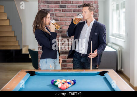 Couple drinking beer next to billiard pool table. Stock Photo