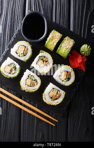 set of Japanese rolls of green dragon with avocado, omelet, sesame and cucumber closeup on a plate on the table. Vertical top view from above Stock Photo