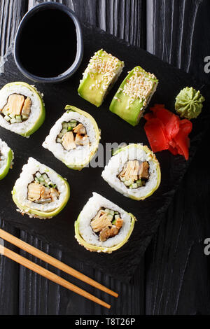 Green japanese roll with avocado, tamago omelette, sesame and cucumber closeup on a plate on the table. Vertical top view from above Stock Photo