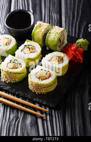 set of Japanese rolls of green dragon with avocado, omelet, sesame and cucumber closeup on a plate on the table. vertical Stock Photo