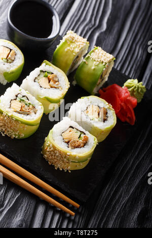 Japanese rolls green dragon with avocado, omelette tamago, sesame and cucumber closeup on a plate on the table. vertical Stock Photo
