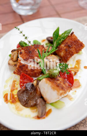 Coalfish fillet with mushrooms and asparagus on plate Stock Photo