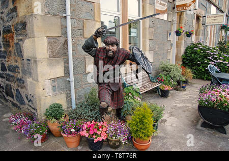 Oban, United Kingdom - February 20, 2010: warrior statue on building corner with pot plants. Town house with bench and flowers in yard. Victorian style architecture and design. Hotel accommodation. Stock Photo