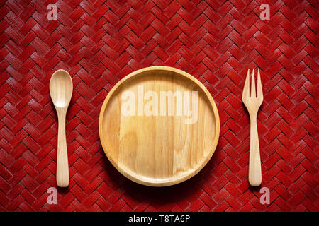 Blank wooden dish with spoon and fork on texture of woven bamboo. Top view and copy space for text. Stock Photo