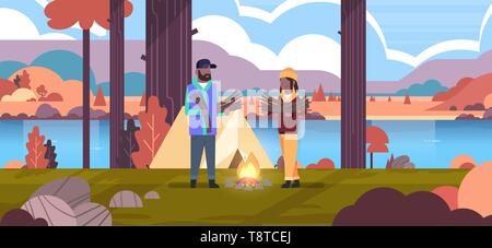 couple tourists hikers holding firewood african american man woman organizing fire n camp tent hiking camping concept autumn landscape nature river Stock Vector