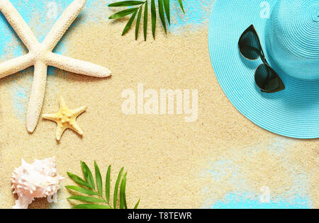 Tropical Background. Palm Trees Branches, hat with starfish and seashell on sandy background. Travel. Copy space Stock Photo